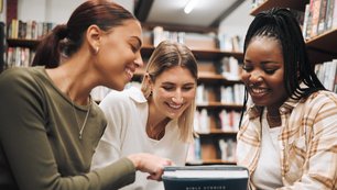 Schülerinnen und Schüler sitzen um ein Buch