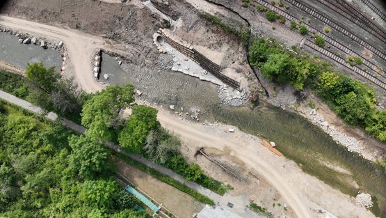 Provisorische Rohrbrücke und neu verlegter Regenwasserkanal vor rückgebautem Wehr (rechts)