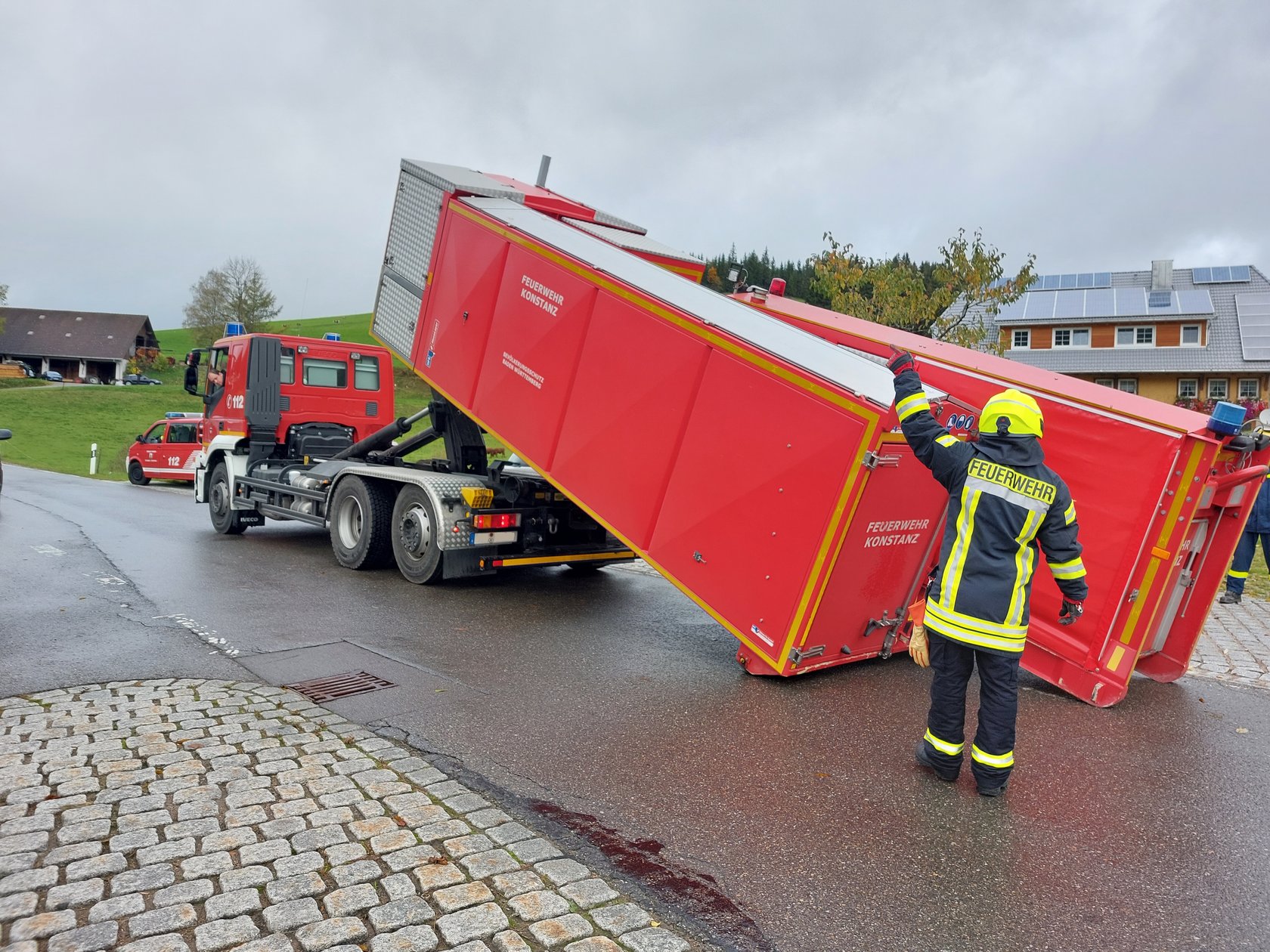 Ein Feuerwehrmann steht an einem umgekippten Lastwagen