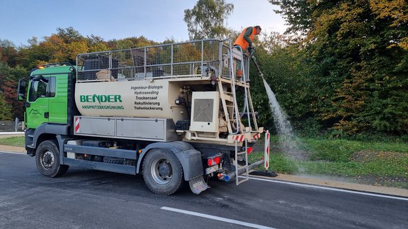 Ein Mann steht auf einer Baumaschine und hält einen Gartenschlauch