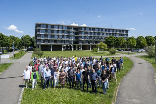Mitarbeitende stehen vor einem Gebäude