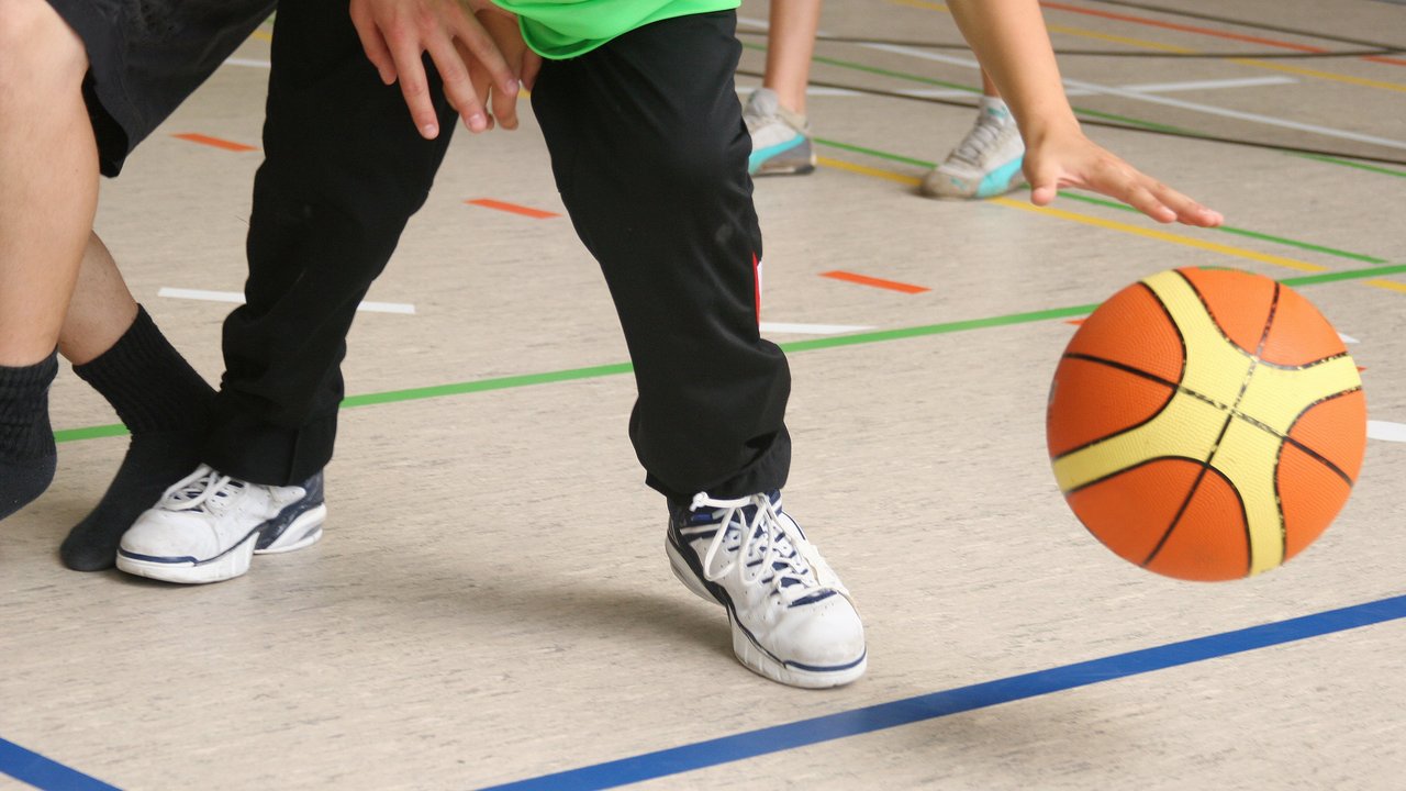Ein Junge spielt in einer Halle Basketball