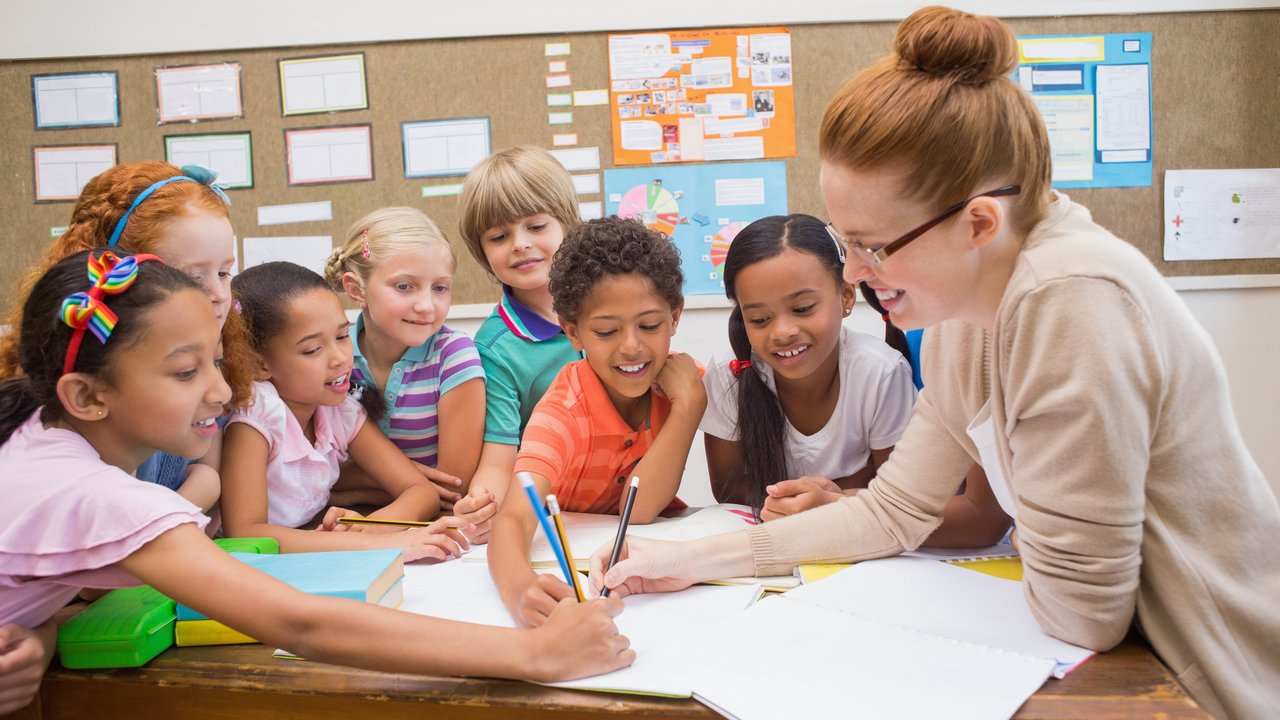 Mehrere Grundschüler malen mit ihrer Lehrerin ein Bild