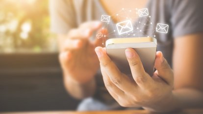 Eine Person mit einem Smartphone in der Hand, darüber Briefsymbole