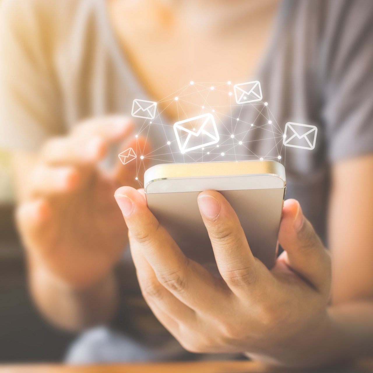 Eine Person mit einem Smartphone in der Hand, darüber Briefsymbole