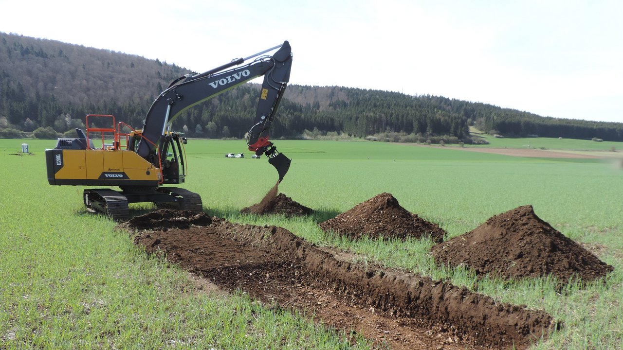 Bagger gräbt auf Wiese nach archäologischen Relikten