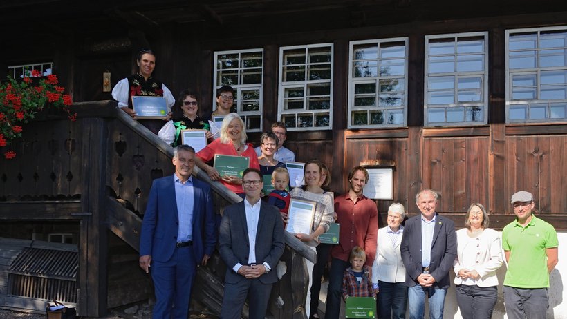 Menschen stehen vor einem Bauernhaus auf einer Treppe