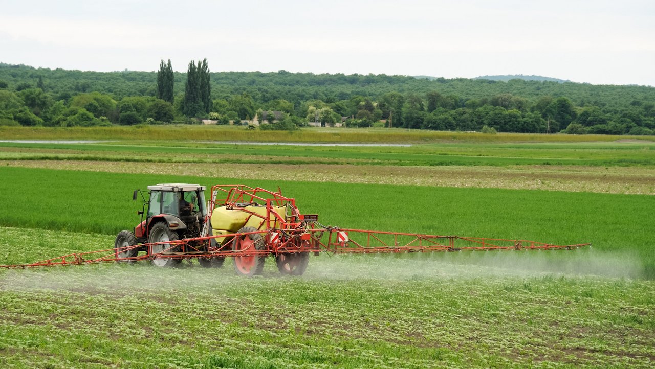 Landwirt mit Traktor sprüht Pestizide oder Dünger auf das Feld