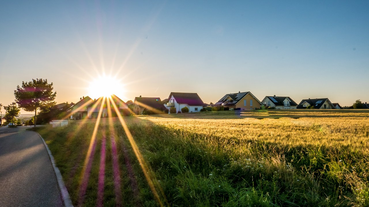 Die Sonne steht über einem landwirtschaftlichen Feld