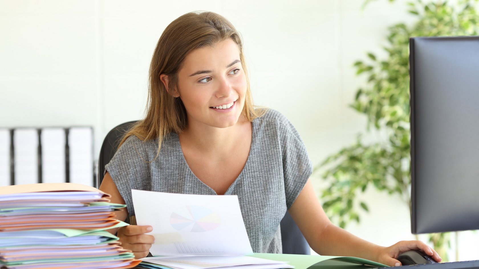 Das Bild zeigt eine junge Frau bei der Arbeit vor dem Rechner