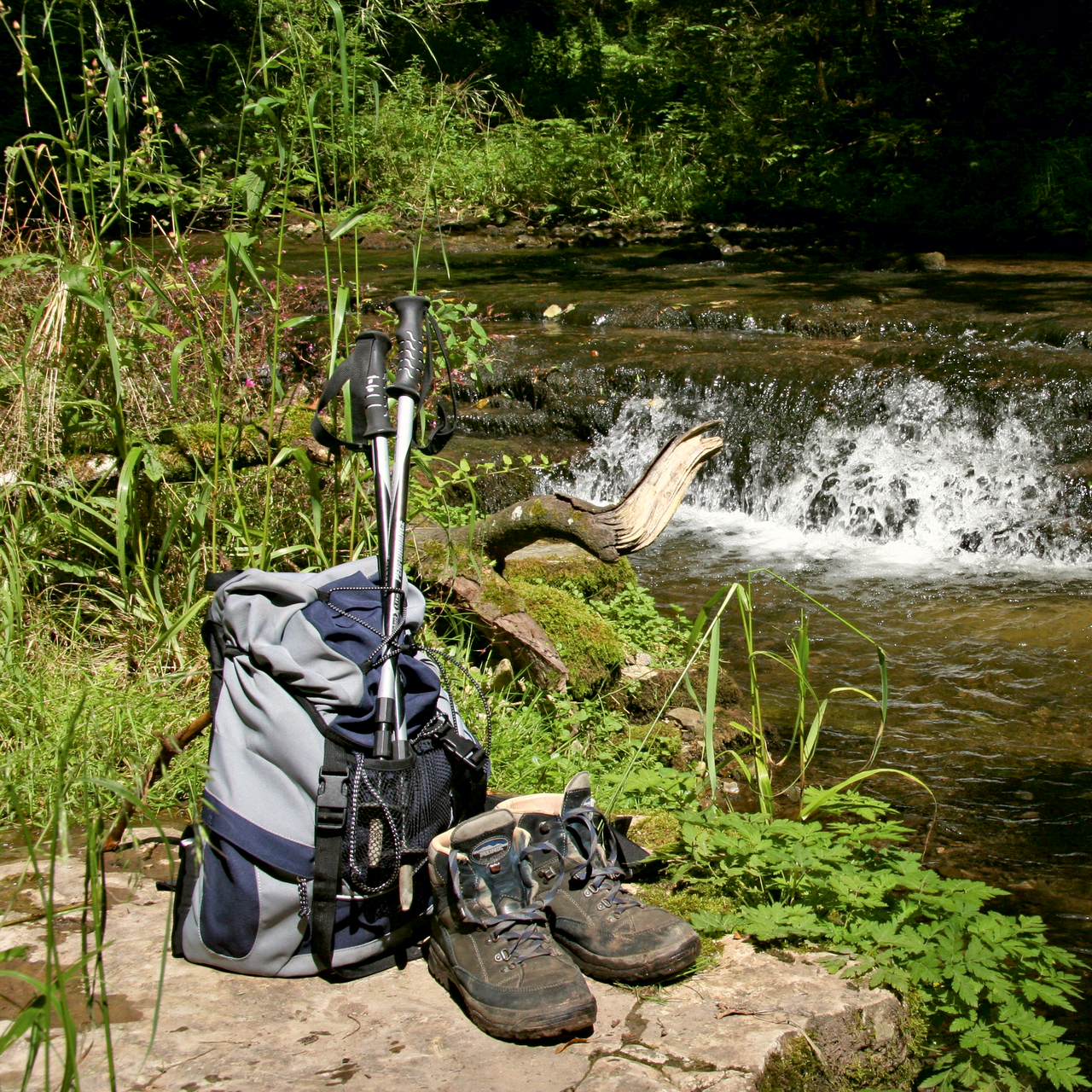Wanderschuhe Schuhe und Rucksack vor einem Gewässer