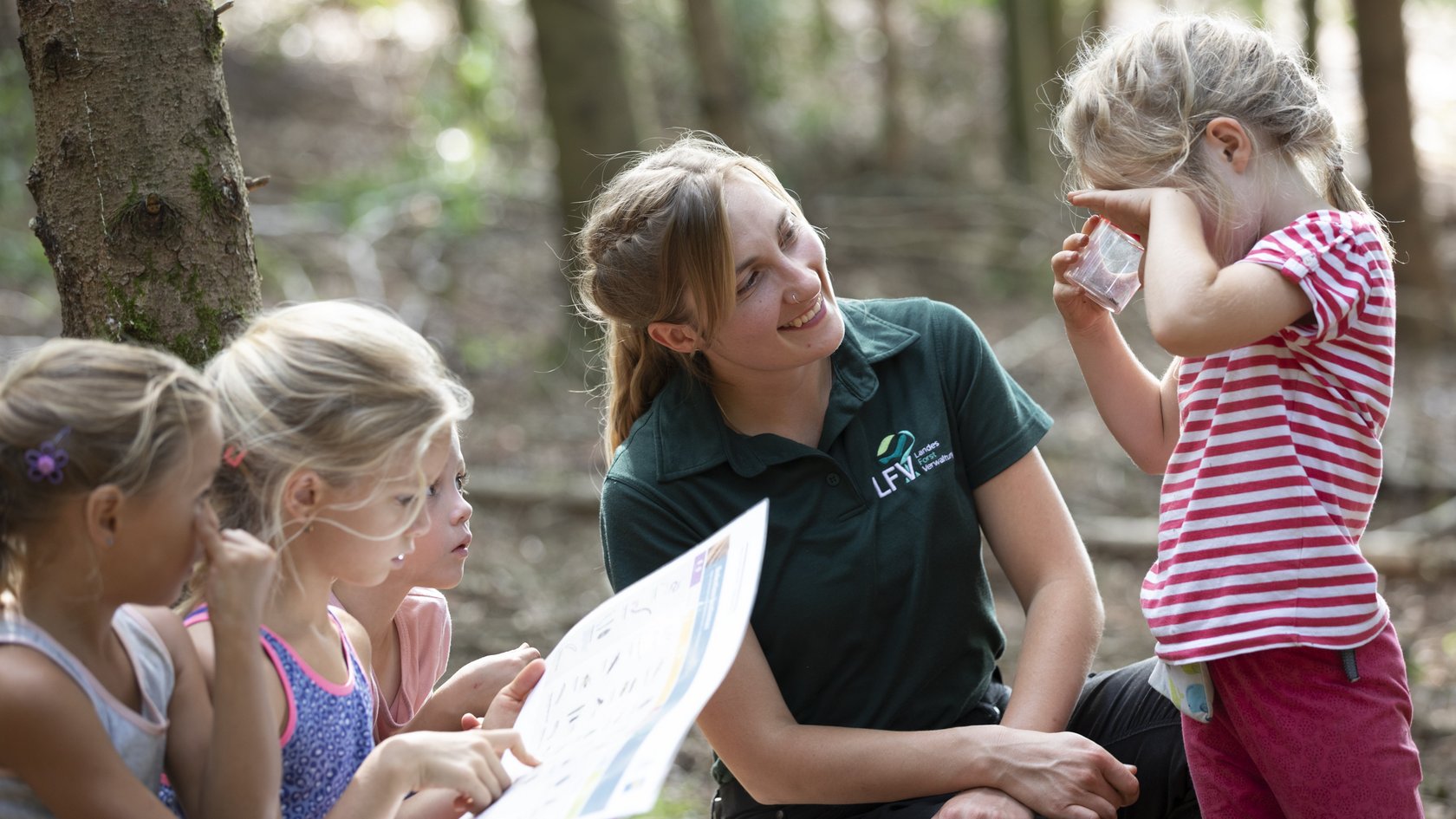 Eine Frau aus der Landesforstverwaltung erklärt Kindern die Funktionen des Waldes 