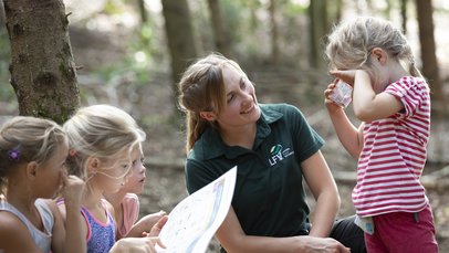 Eine Frau aus der Landesforstverwaltung erklärt Kindern die Funktionen des Waldes 