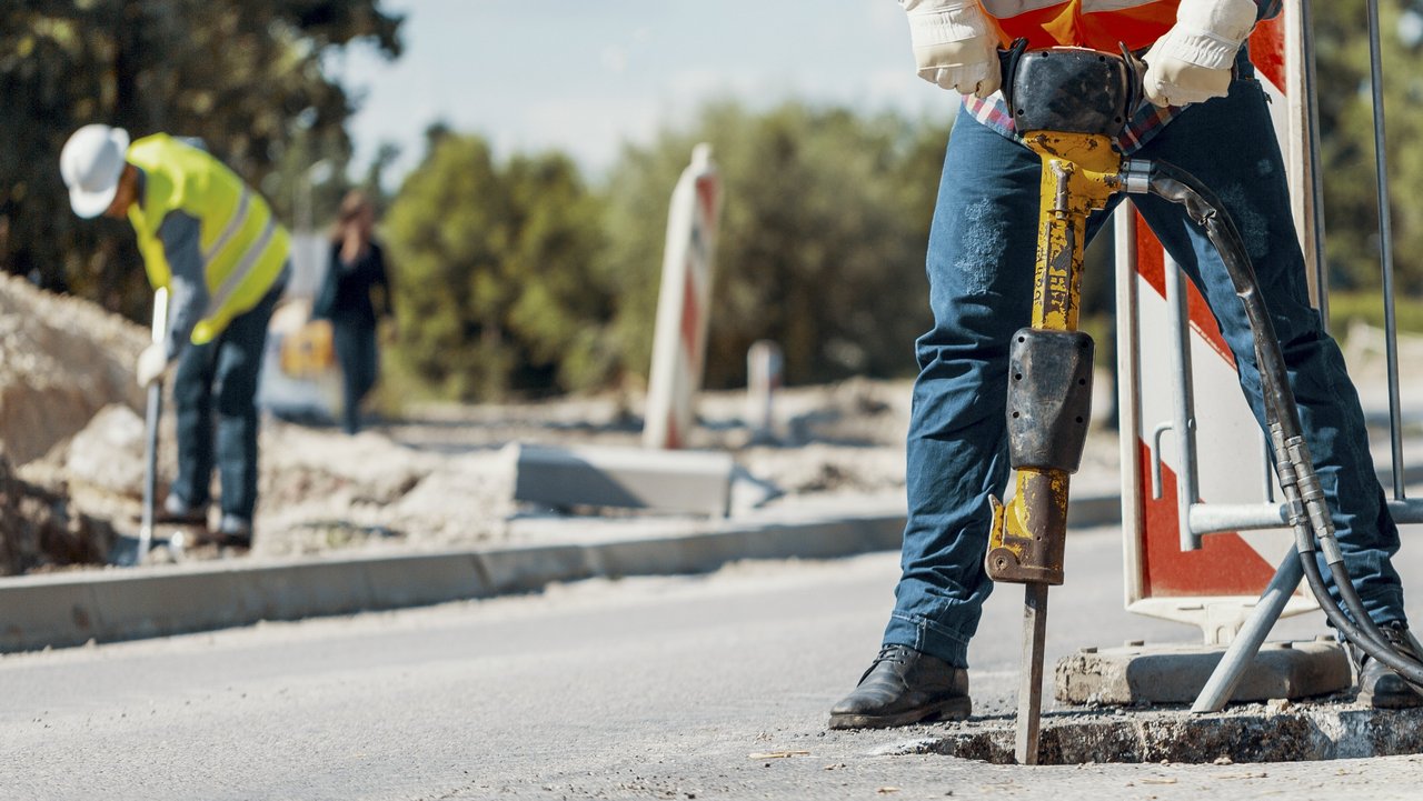 Eine Person mit einem Bohrhammer auf einer Straße