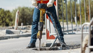 Eine Person mit einem Bohrhammer auf einer Straße