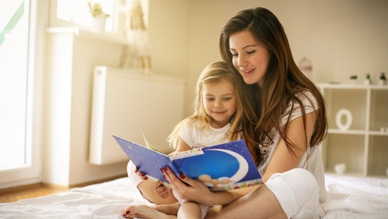 Eine Butter liest mit ihrer kleinen Tochter gemeinsam ein Buch