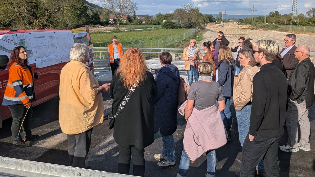 Fachleute des RP stehen mit Bürgermeister und Gemeinderat auf einer Brücke und erklären die Pläne