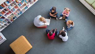 Kinder sitzen im Kreis, ihnen wird vorgelesen