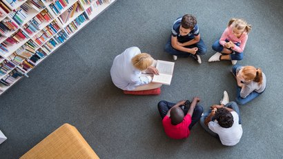Kinder sitzen im Kreis, ihnen wird vorgelesen
