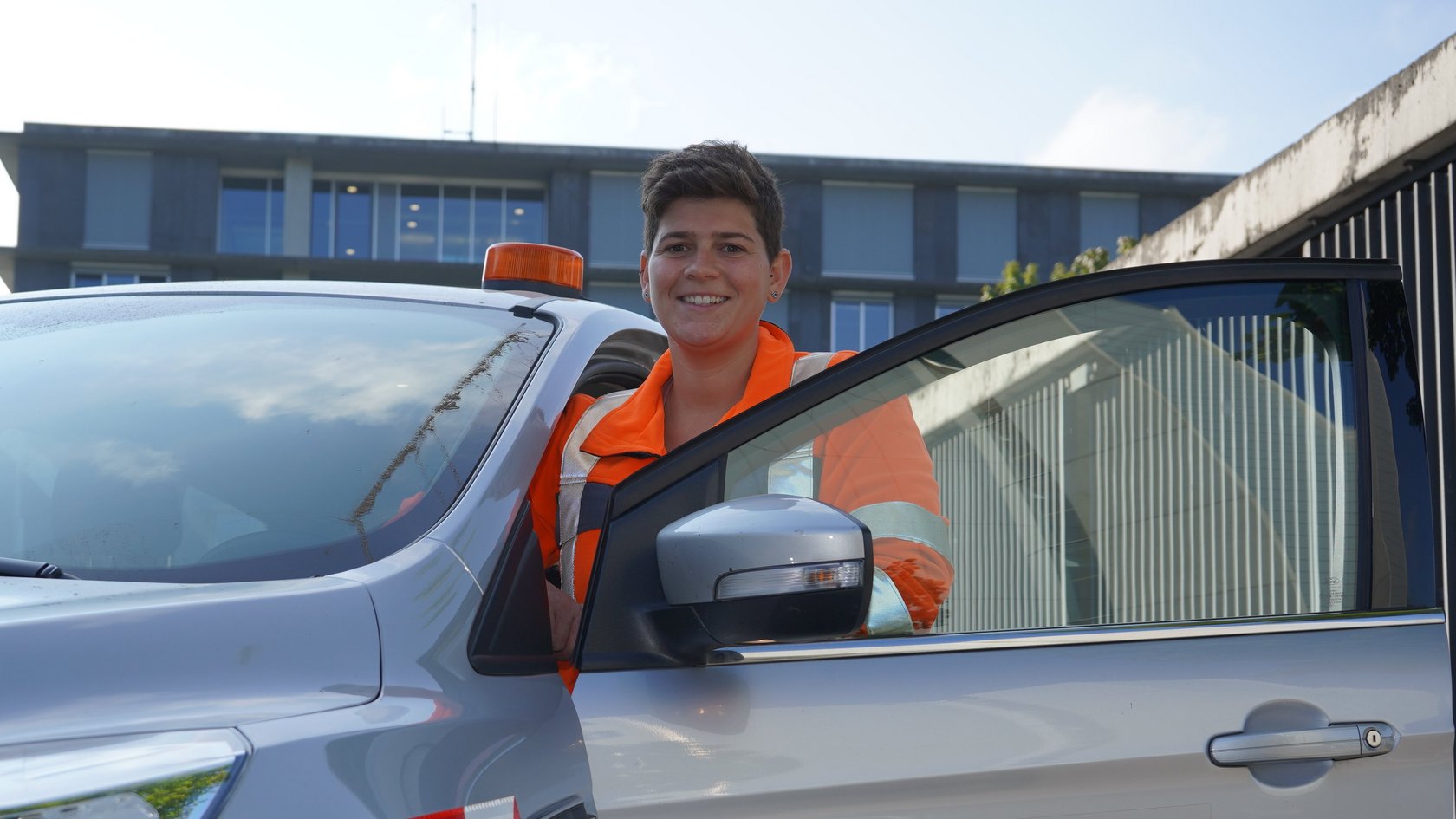 Junge Frau mit Warnweste bei einem Auto