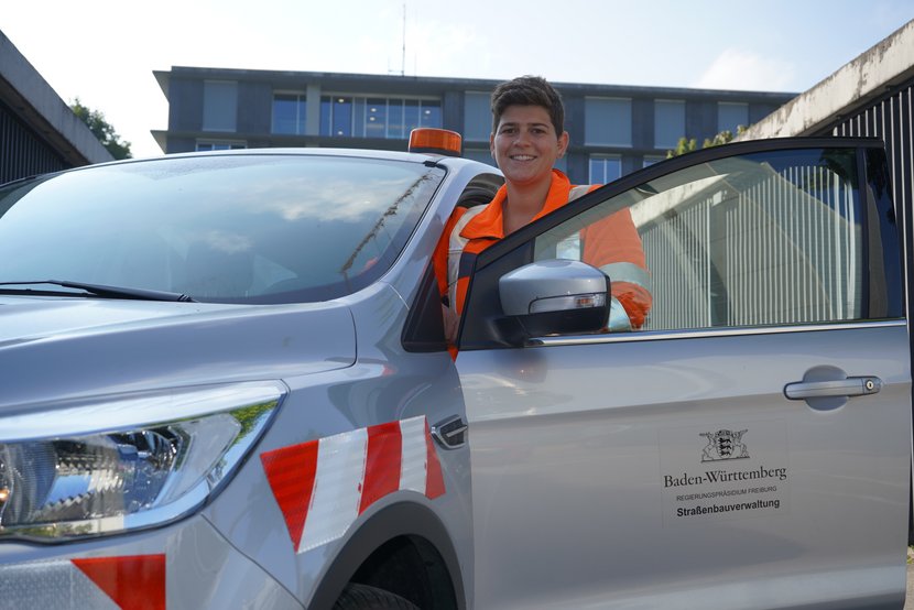 Junge Frau mit Warnweste bei einem Auto