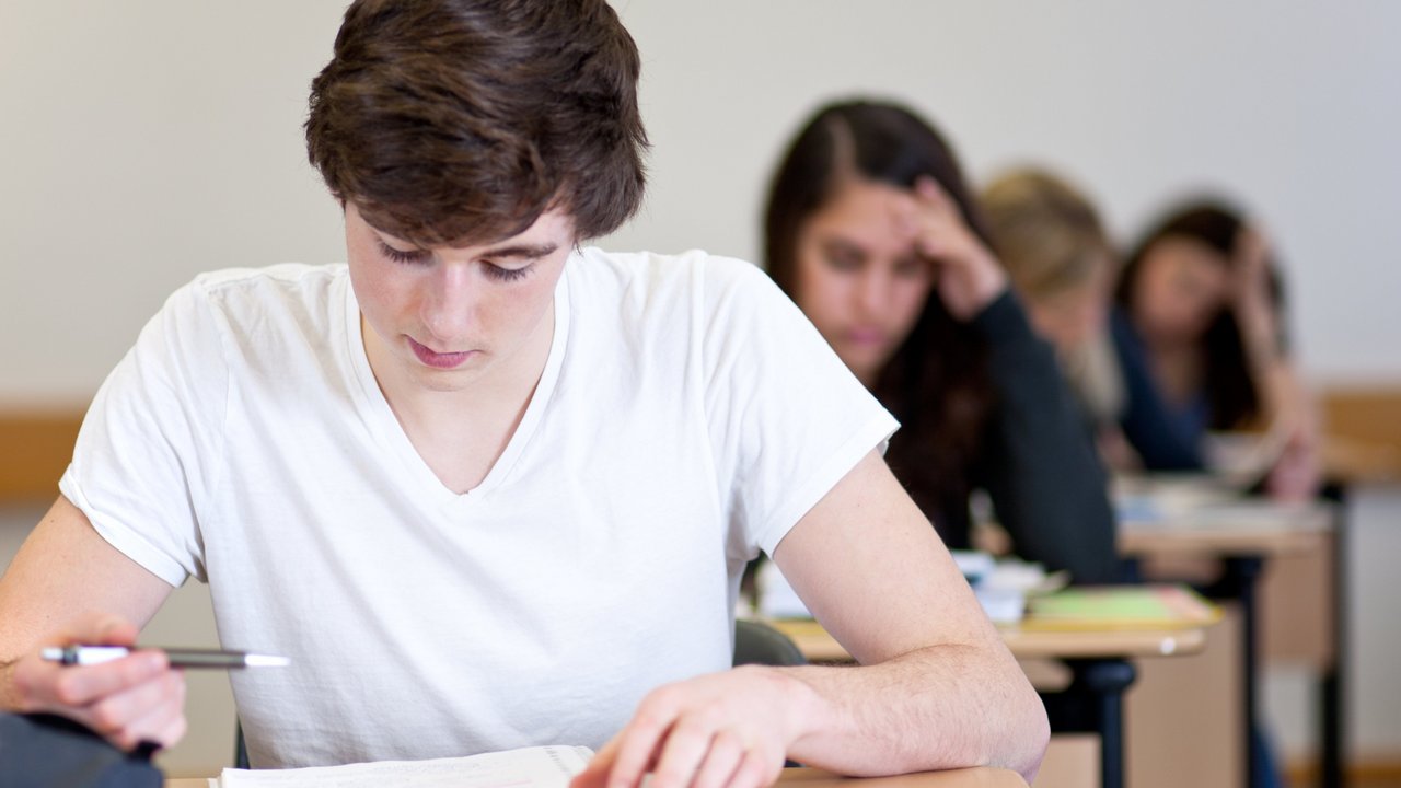 Abiturprüfung Mehrere Schülerinnen und Schüler sitzen im Klassenraum
