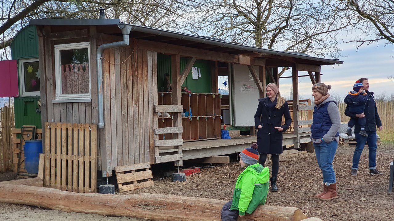 Bauwagen des Waldorf-Naturkindergartens im Burkheimer mit Müttern und Kind im Sandkasten