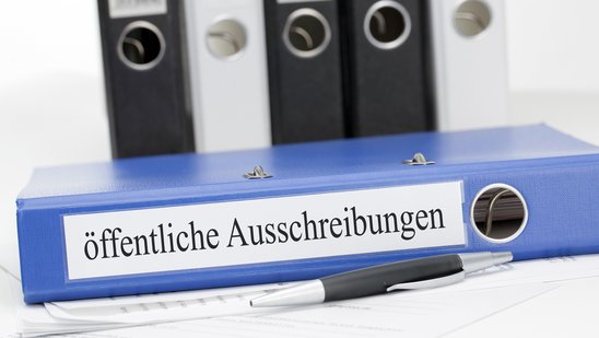 Ordner mit Ausschreibungen auf dem Rücken