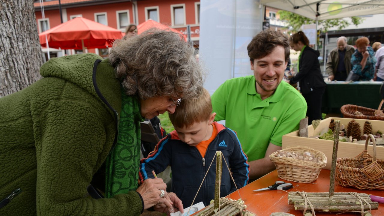 Ein Ranger sitzt neben einer Familie, die ein Holzboot bastelt