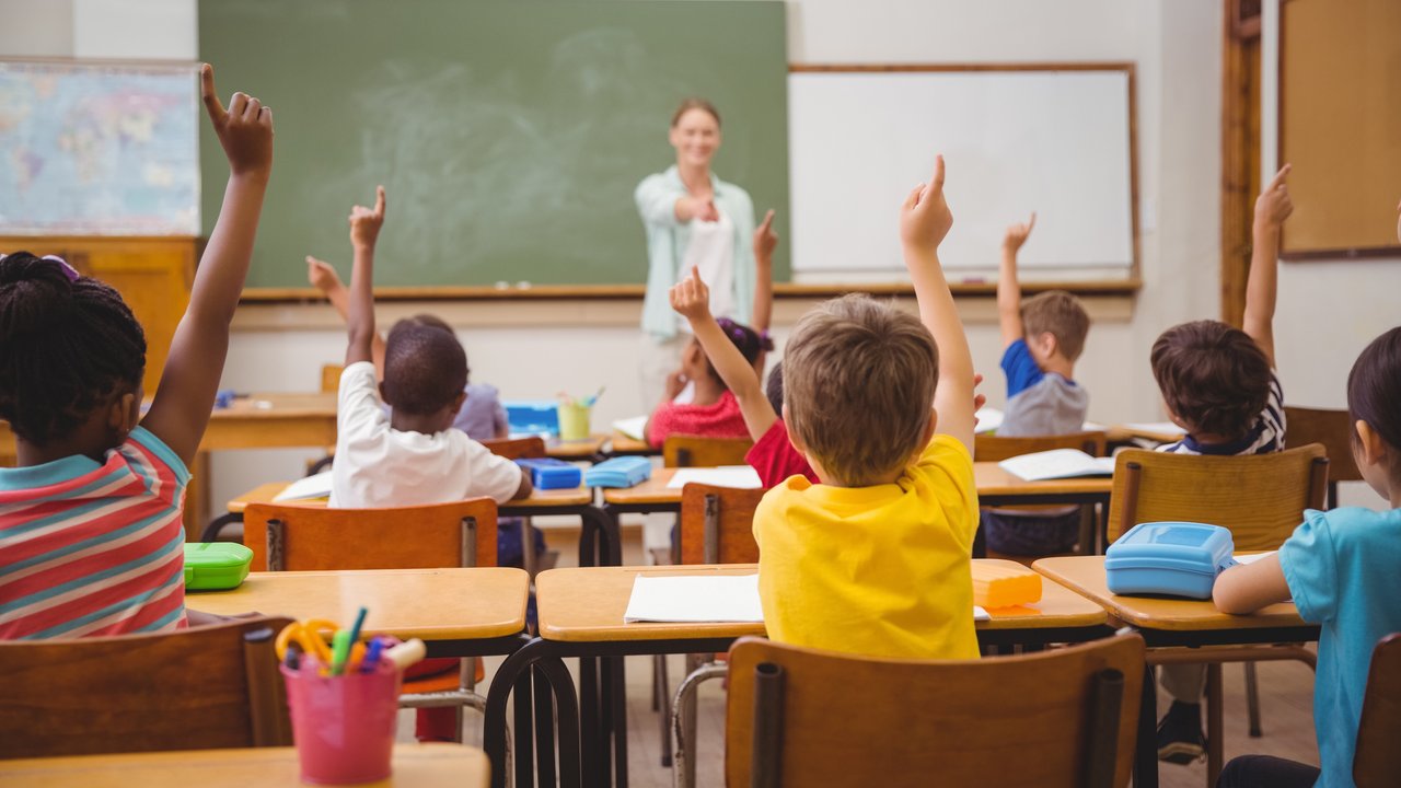 Klassenraum mit Kindern, die sich melden