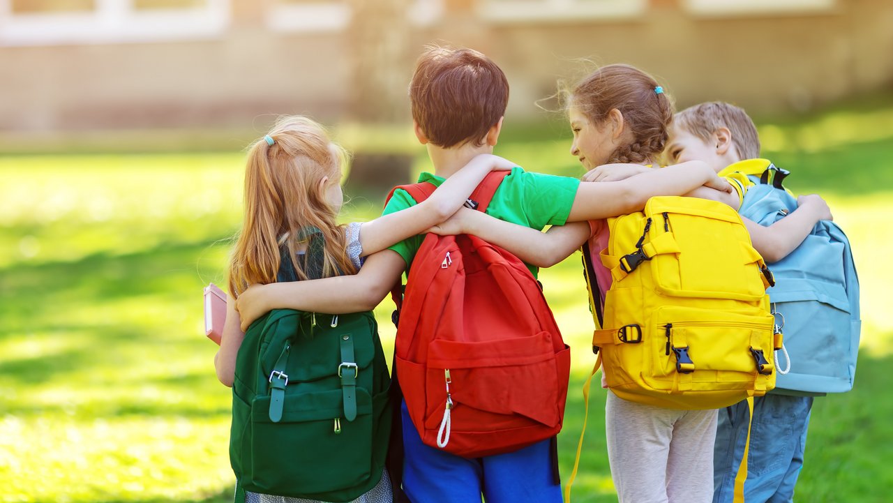 Kinder mit Schulranzen umarmen sich
