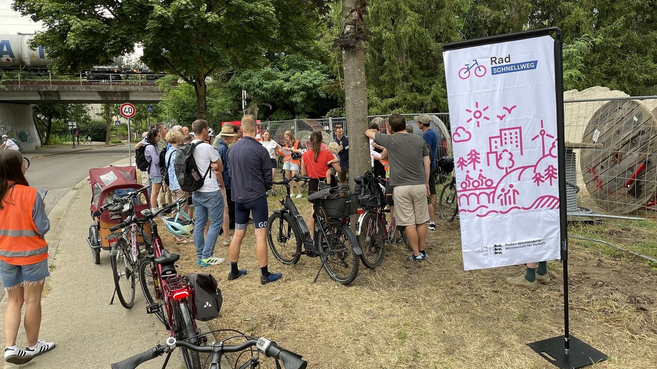 Mehrere Radfahrer und der Planer des RPF neben einer Beachflag zum Radschnellweg