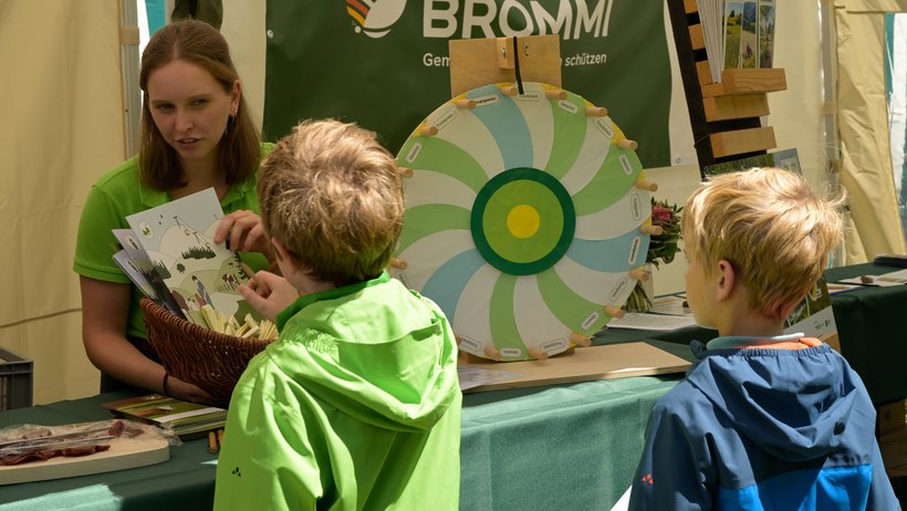 Eine Kollegin des Biosphärengebiets Schwarzwald erklärt Kindern das Malbuch