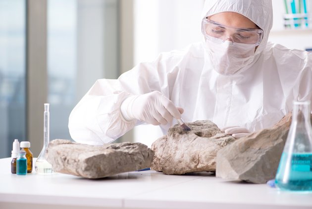 Eine Frau in Schutzkleidung untersucht Gesteinsarten im Labor